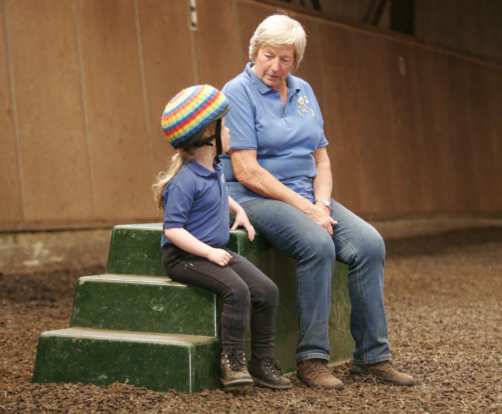 helper and rider sitting on mounting block in conversation