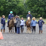 Two ponies and riders with side walkers and leaders