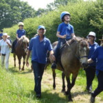 Children riding ponies on country path with side walkers