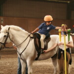 Child on pony reaching for ball on cone