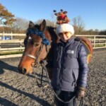 Holding pony wearing Xmas hat waiting for rider to mount